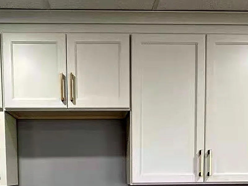 White shaker wall cabinets with crown moulding and brushed gold pulls.